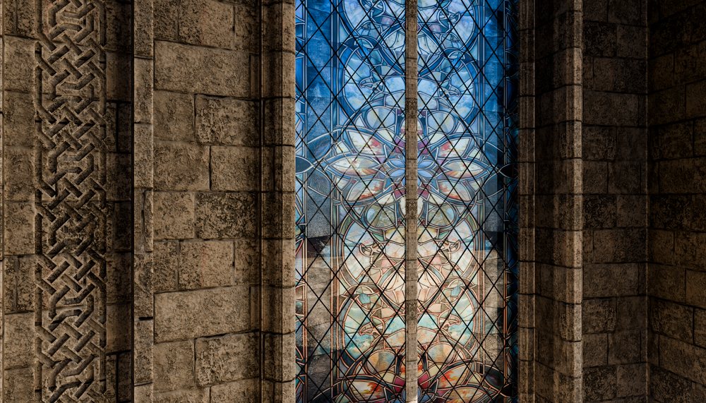 Ornate stained glass window with blue and multicolored glass set in a textured stone wall within a historic church interior.