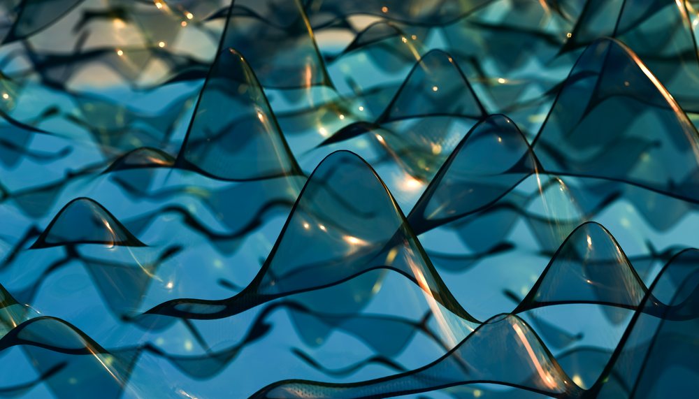 Transparent curved plastic sheets arranged in an artistic wavy pattern creating reflections and shadows on a blue tinted surface.