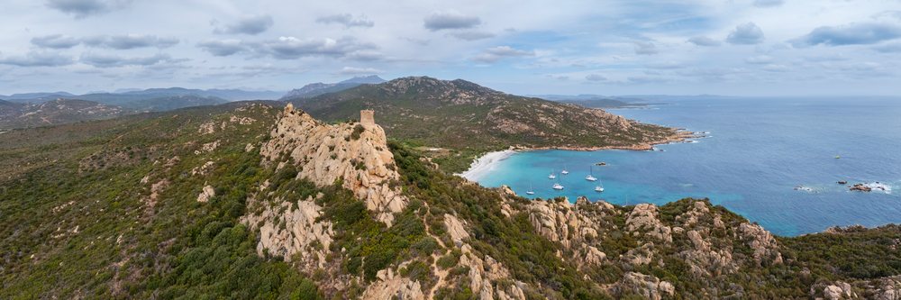 Genoese tower atop a rocky hill ridge overlooks sailboats anchored in the turquoise bay of, Travel Photography, Cala di Roccapina, Corsica, France.
