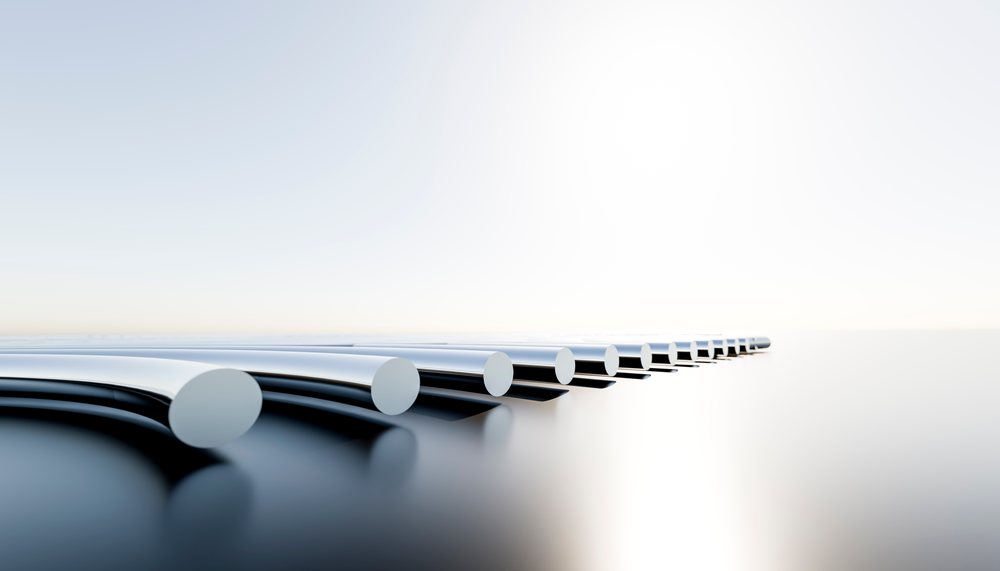 Metal rods with polished chrome ends arranged on a reflective surface in a minimalist setting.