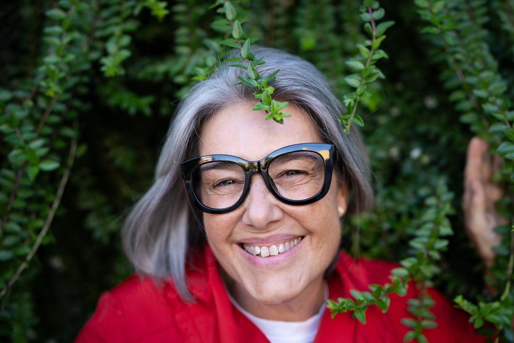 Smiling mature woman with gray hair and black glasses outdoors, Spain.