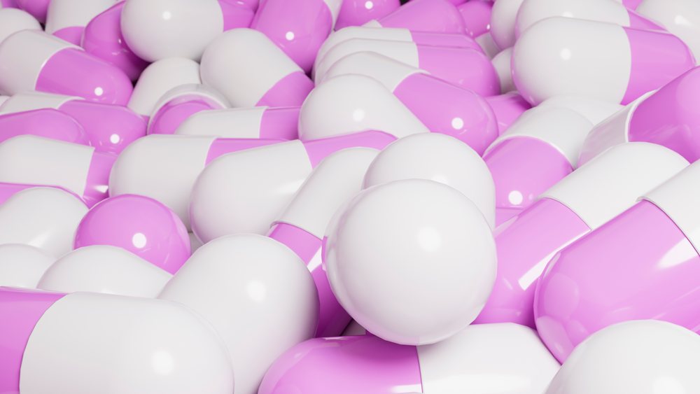 Pile of pink and white pharmaceutical capsules closely packed together.