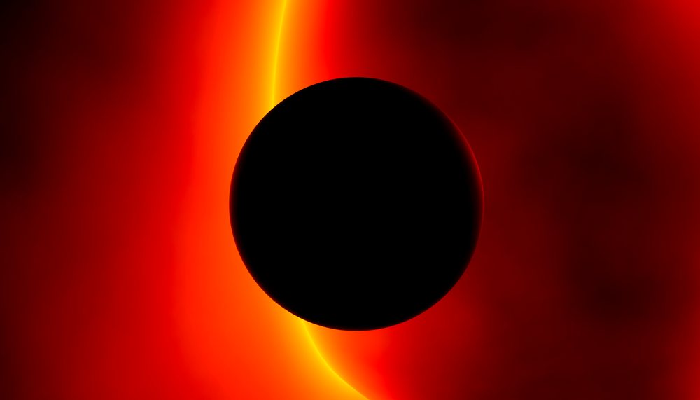 A solar eclipse showing the dark silhouette of the moon covering the sun, with the sun's bright corona visible against a red sky.
