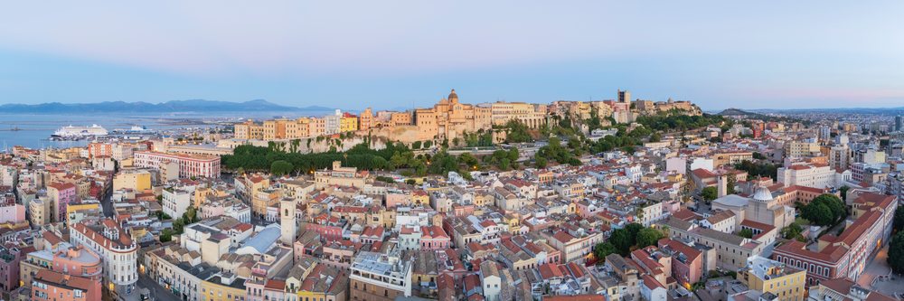 Cityscape of Cagliari's Stampace District with the historic hilltop Citadel overlooking the harbor and cruise ships at sunset, Travel Photography, Sardinia, Italy.