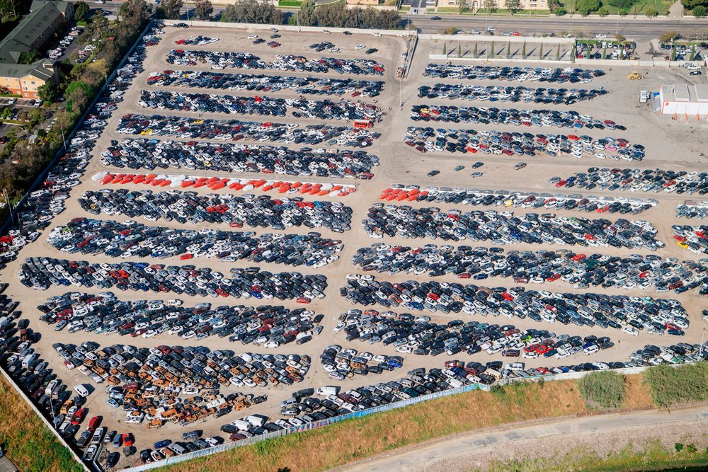 Aerial view of a large parking lot filled with organized rows of cars at a port in Long Beach, CA, USA.