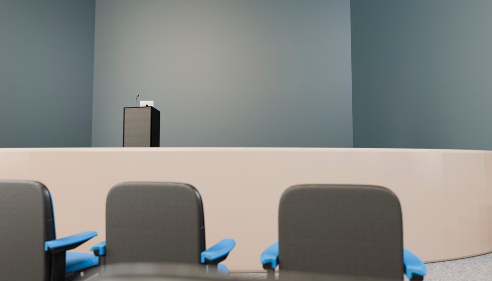 Empty conference room stage with podium and microphone viewed over chairs with blue armrests in a modern event space.