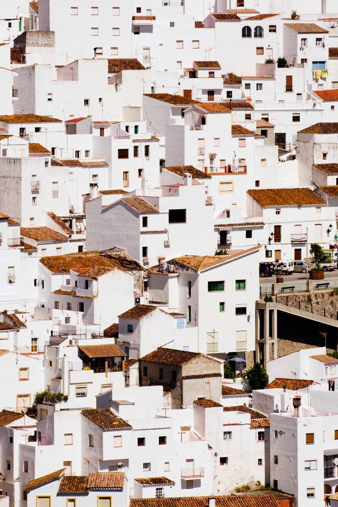 White houses with red tile roofs clustered on a hillside in the Mediterranean hill town of Casares, Andalusia, Adnalusia, Spain.