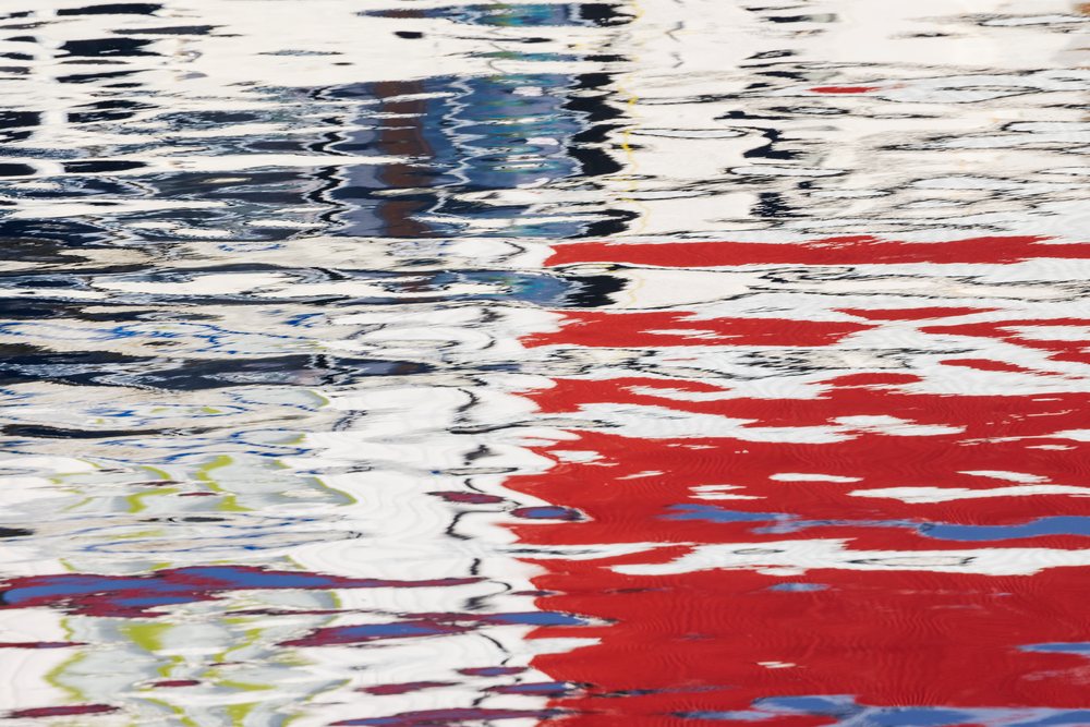 Colorful Reflections ripple and distort on the water surface in the harbour, Landscape, Henningsvaer, Lofoten, Norway.