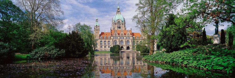 The historic New City Hall Hannover with towers reflects in a pond, Germany.
