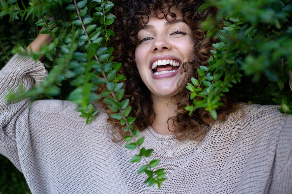 Woman with curly hair smiles warmly, home story, influencer, Spain.