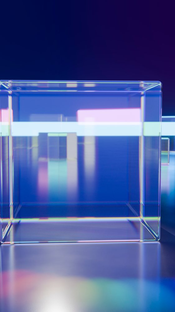 Transparent glass cube reflects colorful lights on a glossy surface against a blue background in a modern abstract setting.