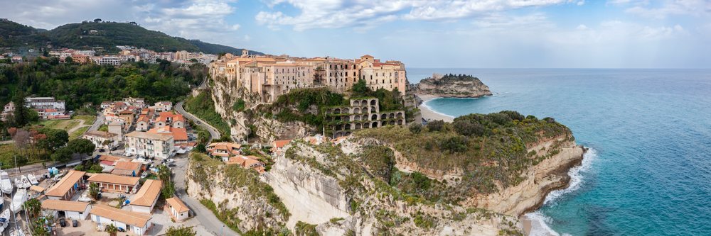 Historic buildings in Tropea perched on cliffs overlooking the Mediterranean Sea, Italy under a partly cloudy sky, Calabria.