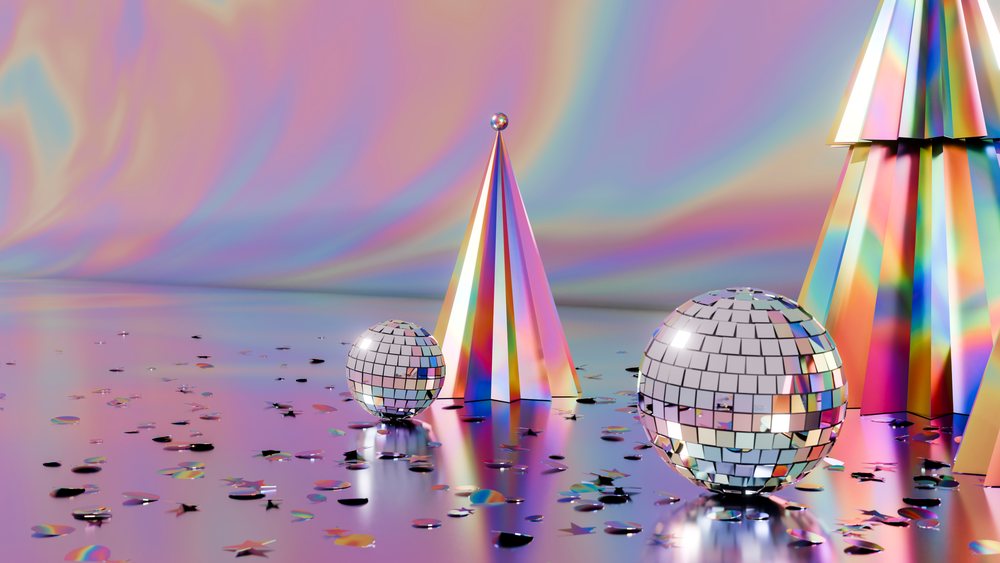 Disco balls and cone-shaped decorations surrounded by confetti on a reflective surface with a rainbow-colored background.