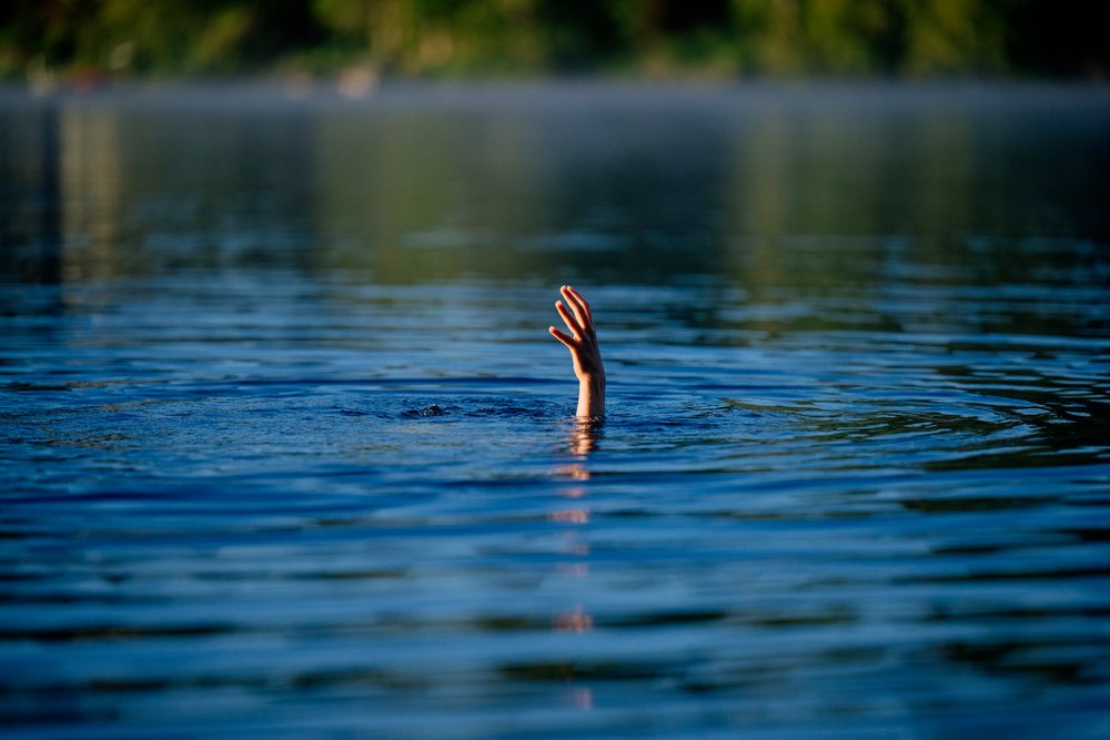 Hand reaching out of the water as a person struggles to stay afloat in a lake, USA.