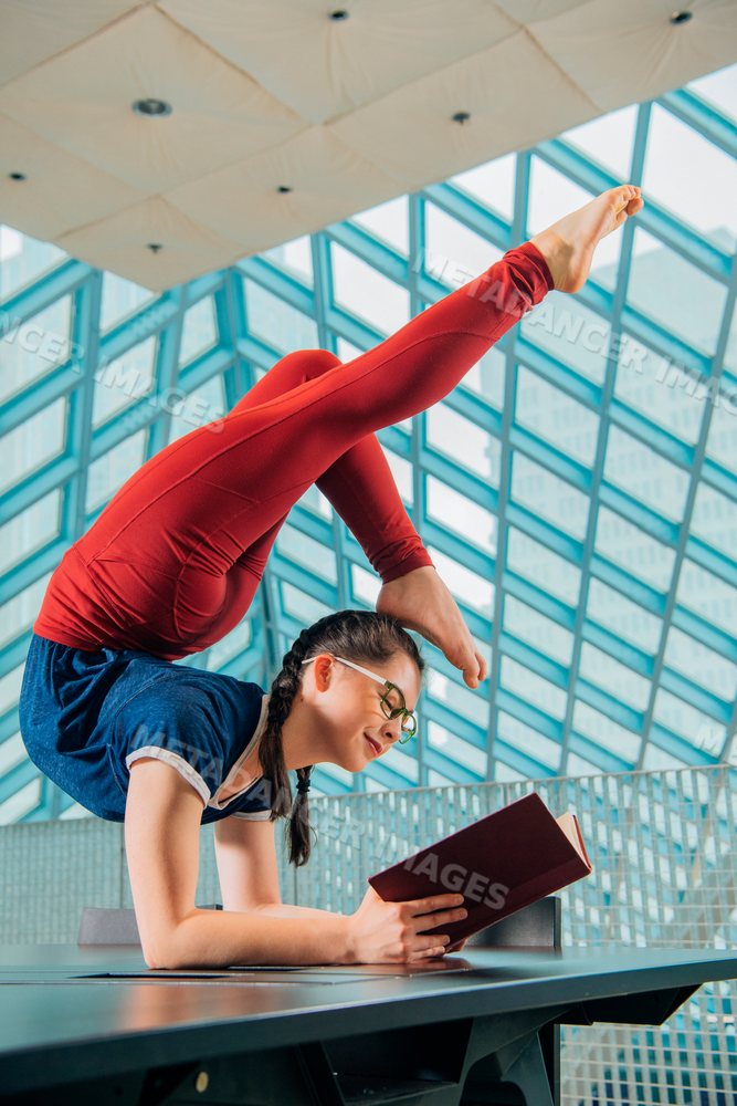 A flexible woman reads a book while balancing