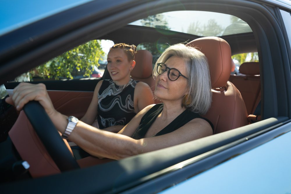 Two women, a driver and passenger, riding in a car on a sunny day, businesswomen, Spain.
