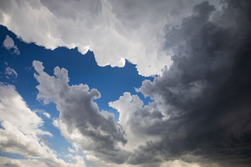 Storm clouds with anvil-shaped edge and blue sky visible overhead in Tornado Alley, Crossroads, New Mexico, USA.