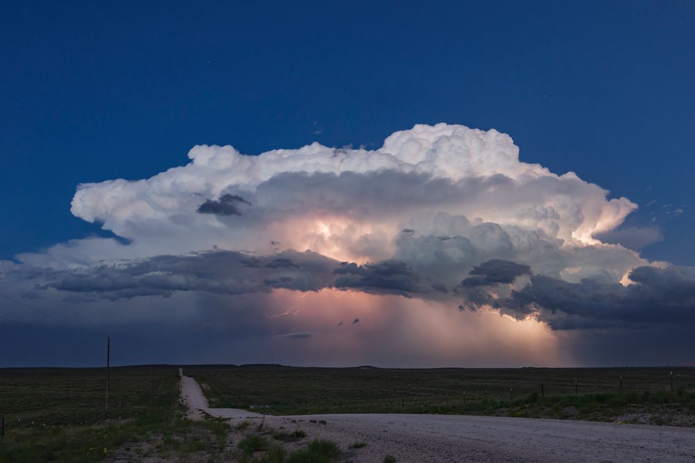 Lightning flashes inside a Supercell storm cloud over open grassy plains in the evening, Nara Visa, New Mexico, USA.