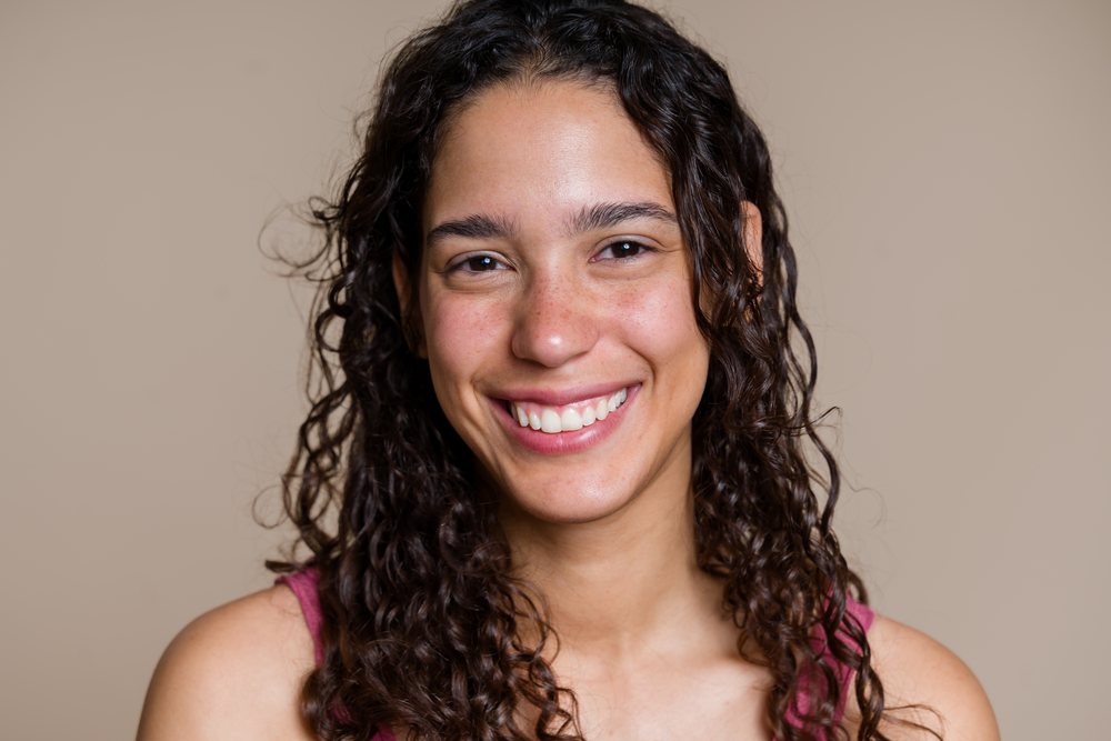 Close-up portrait of a smiling young woman with curly hair during a studio beauty shoot, Spain.