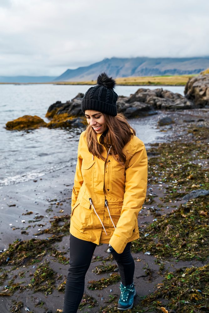 A white woman walking along the rocky coastline