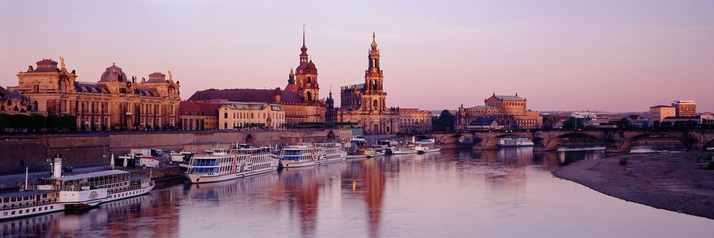 Sunset over Dresden skyline featuring historic buildings, riverboats, and a bridge reflecting on the calm Elbe River water, Dresden Skyline Elbe River Dresden, Germany.
