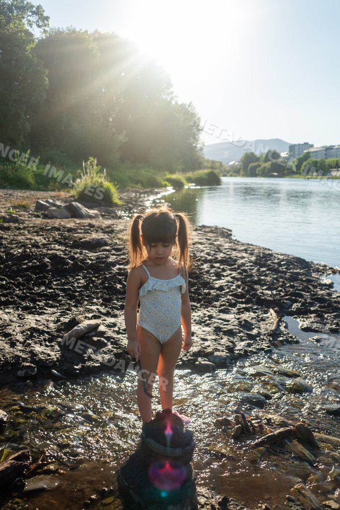 Young white girl playing by the riverbank in Spain on a sunny day