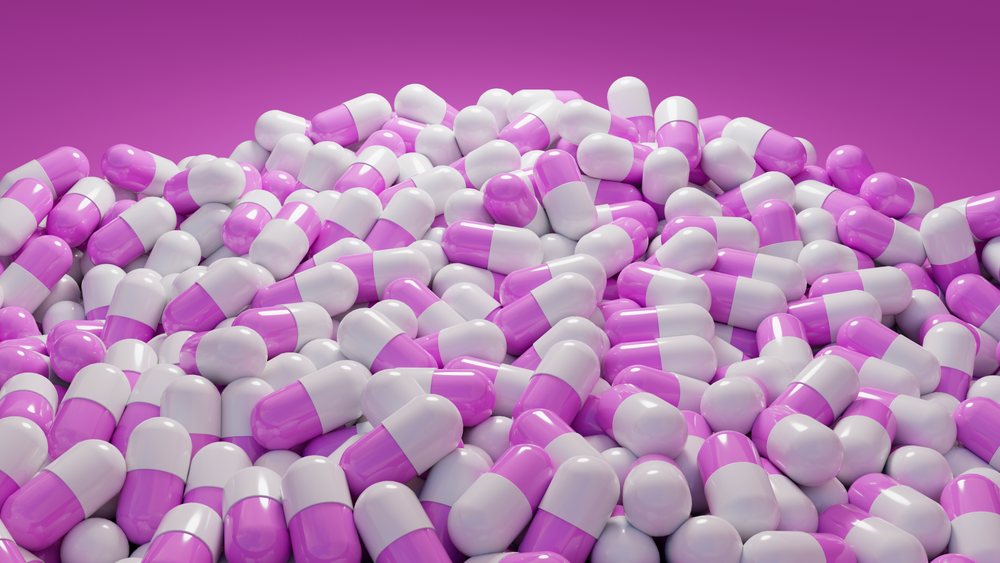 Purple and white capsules piled together creating a large heap in a medical supply setting.