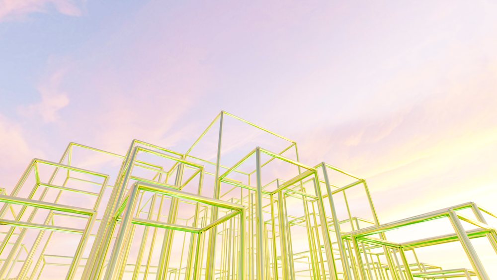 Transparent glass cubes forming a modern geometric art installation against a pastel-colored sky with pink and yellow hues.
