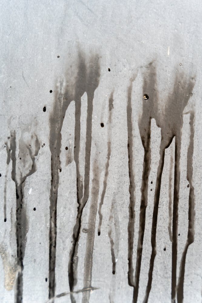 Black liquid stains and vertical drips on a gray textured surface, texture, abstract texture, background, wallpaper, Spain.