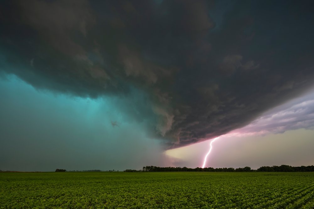 Tornado-warned Supercell storm with Lightning Strike over green field in Tornado Alley under dark storm clouds, Weather, Environmental Issues, Storm Chasing, Charlestown, Illinois, USA.