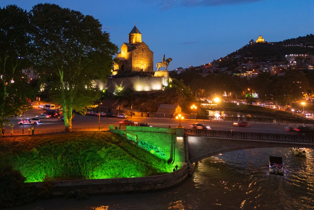 Illuminated Metekhi Church at night overlooking the river and bridge, Georgia cityscape with vehicle traffic and reflections, Cityscapes, Tbilisi.