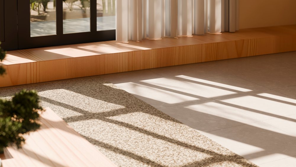 Sunlight creates window shadow patterns on carpet and tile flooring near a wooden ledge and curtains inside a modern interior space.
