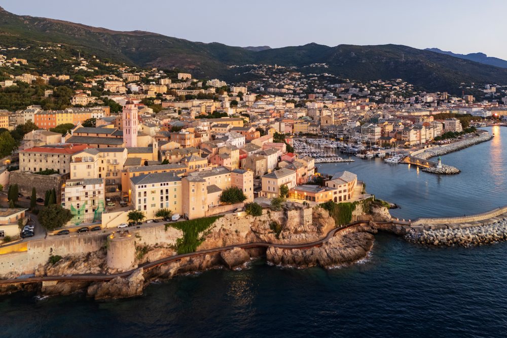 Coastal city of Bastia at Dawn, showing harbor, marina, mountains, and Mediterranean Sea under soft sunrise light, Travel Photography, Corsica, France.