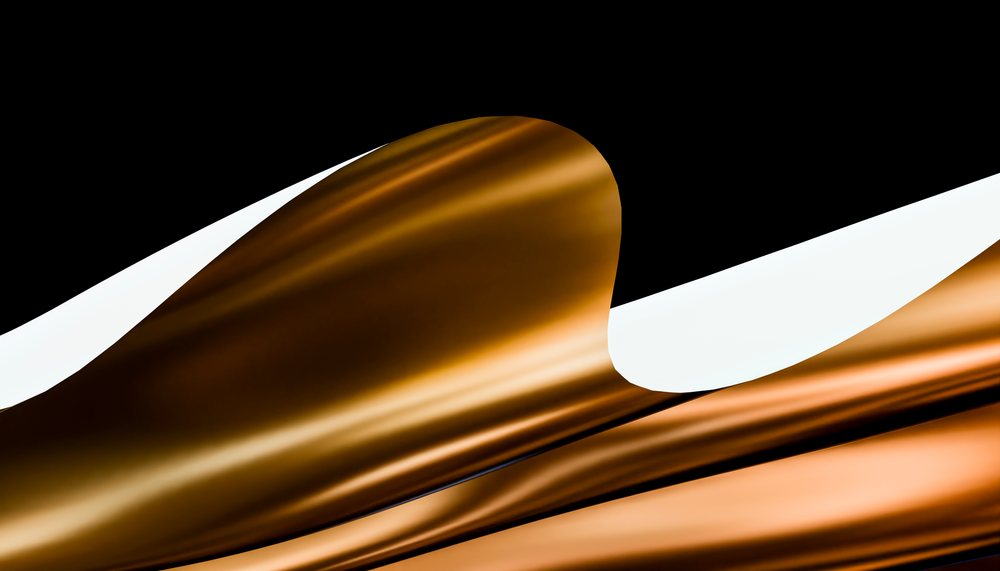 Golden fabric with folded and reflective texture creating an abstract artistic composition on a dark background.