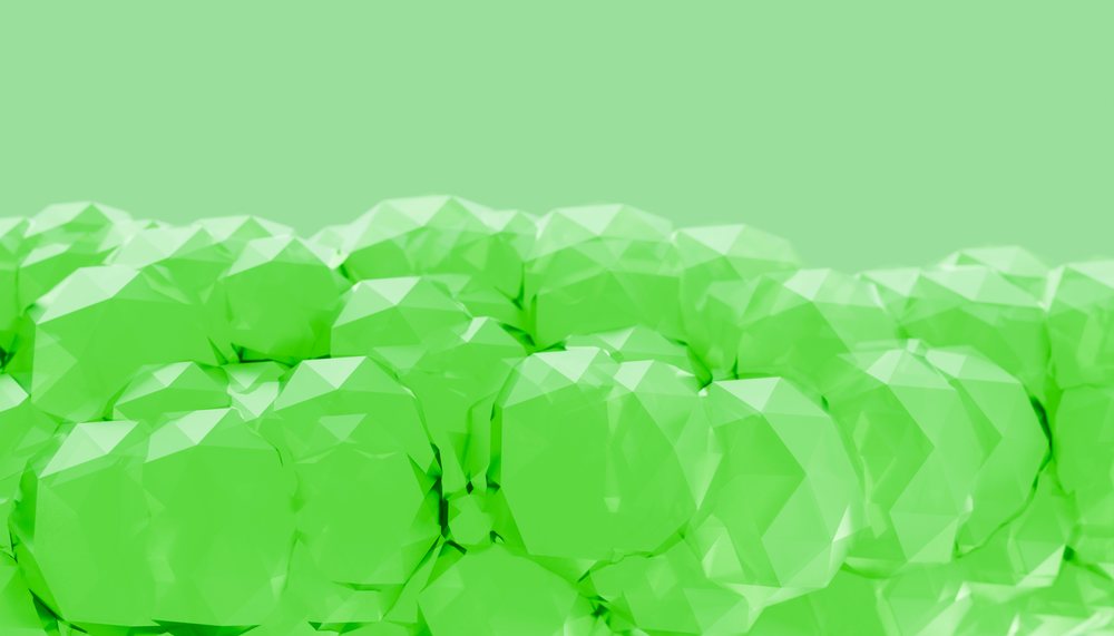 Cluster of green faceted crystals tightly arranged against a solid green background.