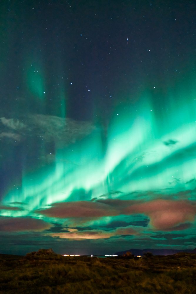 The northern lights illuminate the starry sky over Iceland landscape