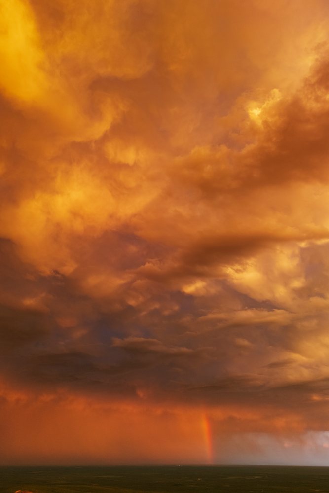 Storm clouds with a rainbow during Sunset over flat plains, Storm Chasing, Weather, Environment, Uvalde, Texas, USA.