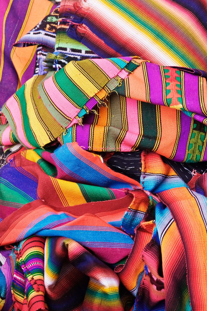 Colorful handwoven blankets folded and displayed on a market stall, Antigua, Guatemala.