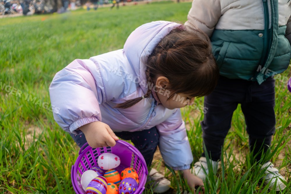 A young white girl collects colorful eggs during an outdoor egg hunt