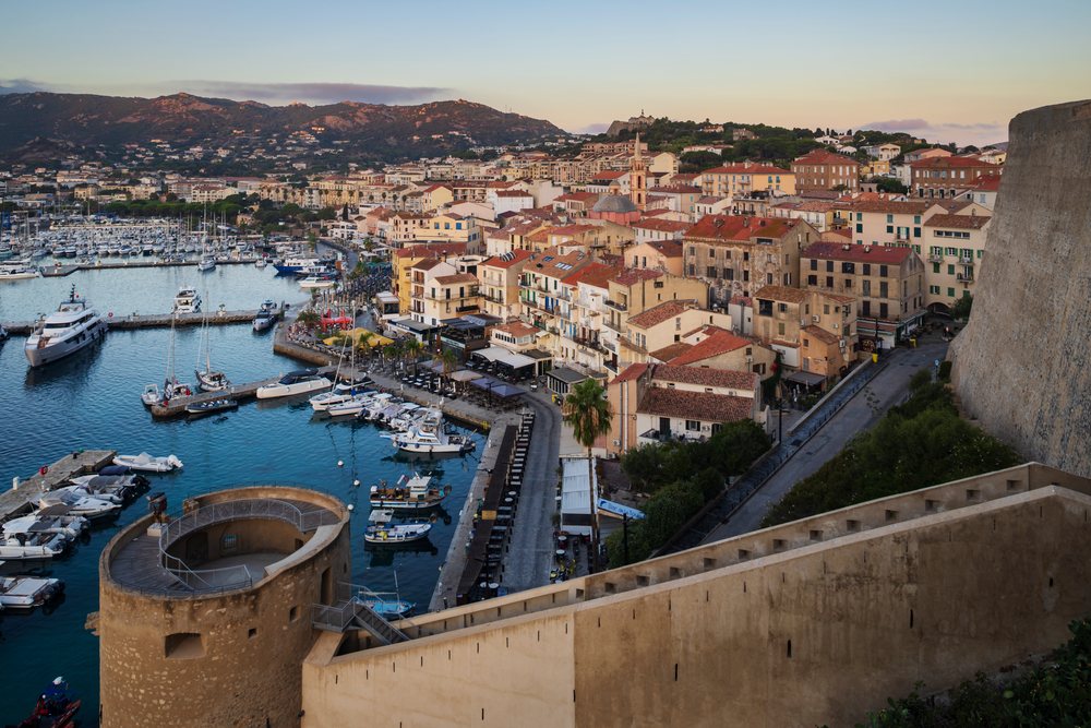 Harbour of Calvi with docked boats and historic Citadel walls at Sunrise along the waterfront, Travel Photography, Corsica, France.