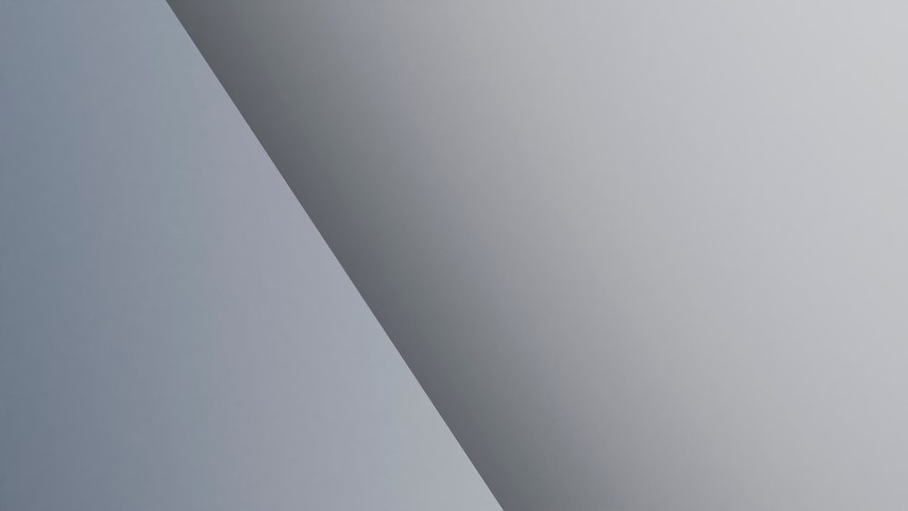 Gray surface with a diagonal shadow creating an abstract minimalist composition.