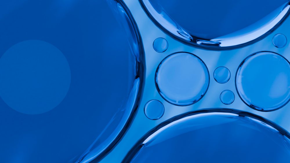 Close-up view of a blue liquid surface with circular bubbles and reflections forming an abstract pattern.