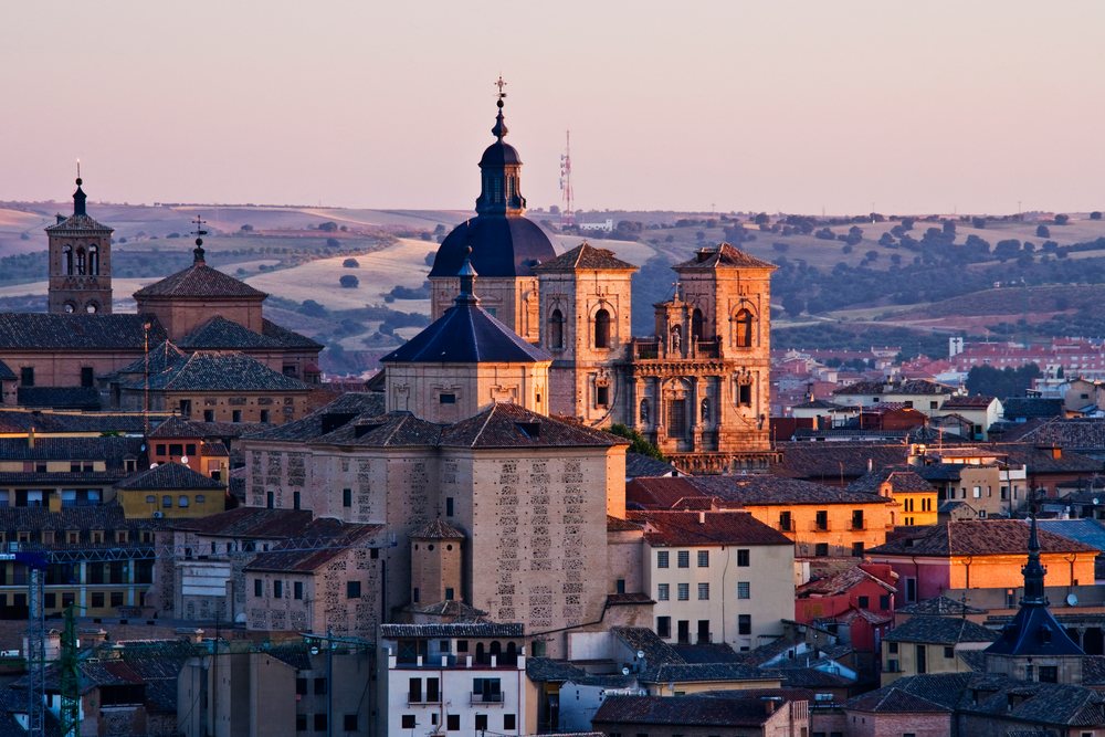Cityscape of toledo with historic buildings and church domes at sunset, Spain.