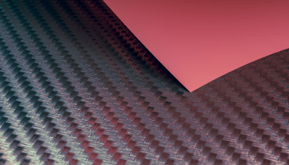 Close-up view of a carbon fiber textured fabric with a red paper corner.
