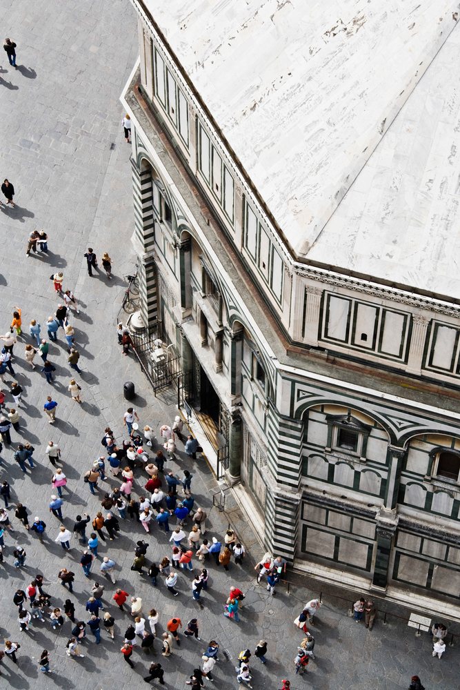 Crowd of tourists gathers outside the Battistero di San Giovanni with its historic marble facade, Florence, Italy.
