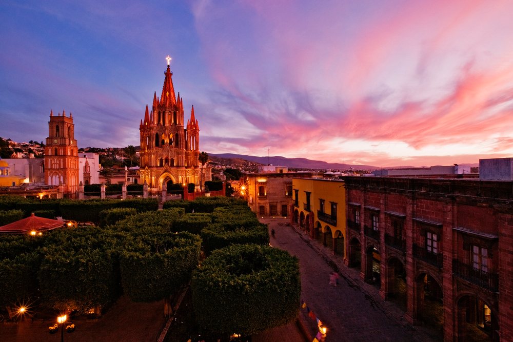 San Miguel de Allende town square and cathedral illuminated at dusk under a colorful sky, Mexico.