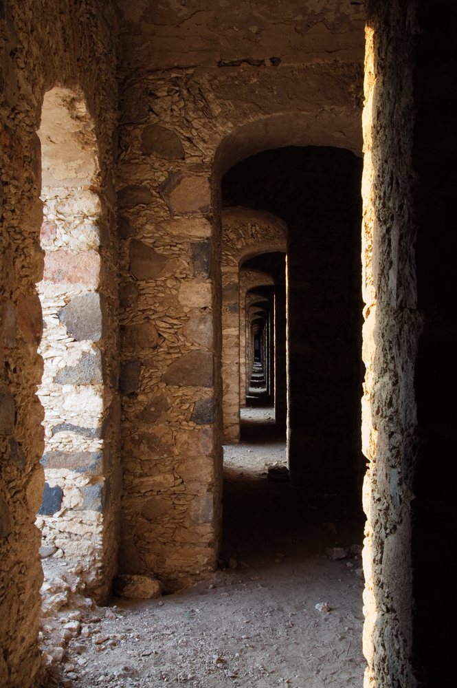 Sunlit corridor of old stone ovens with repeated arched openings and weathered walls, Guanajuato, Mexico.