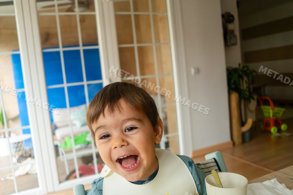 Happy toddler white boy laughing during mealtime