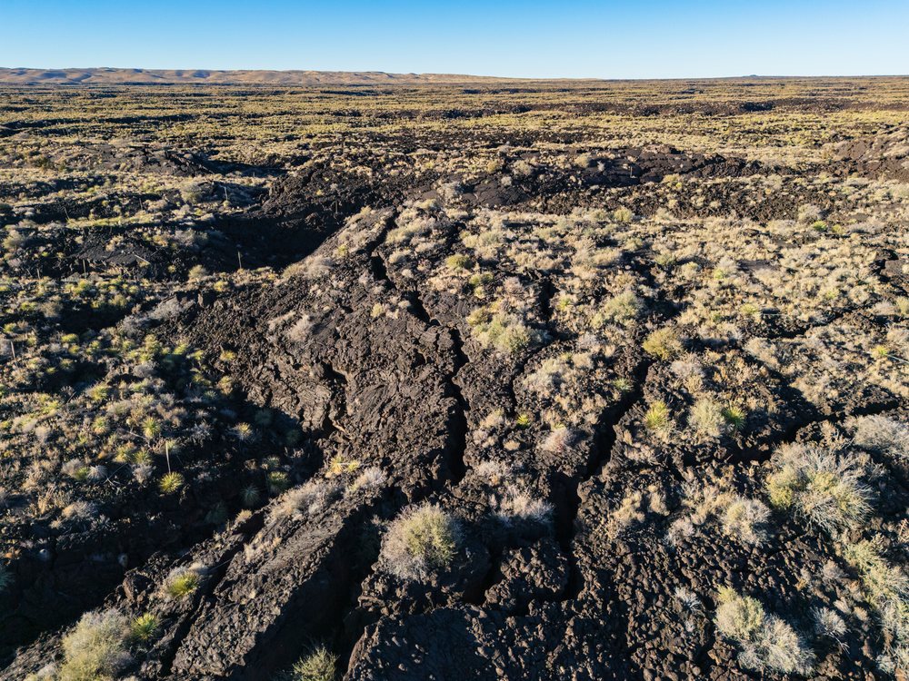 Aerial view of volcanic Lava Field with dry rocky ground and scattered desert vegetation at El Malpais National Monument, landscape, wildlife, Carrizozo, New Mexico, USA.