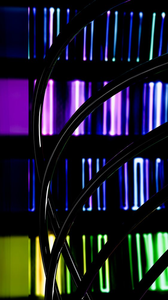 Glossy black curved tubes contrasted against colorful vertical light bars in purple, blue, green, and yellow against a dark background.
